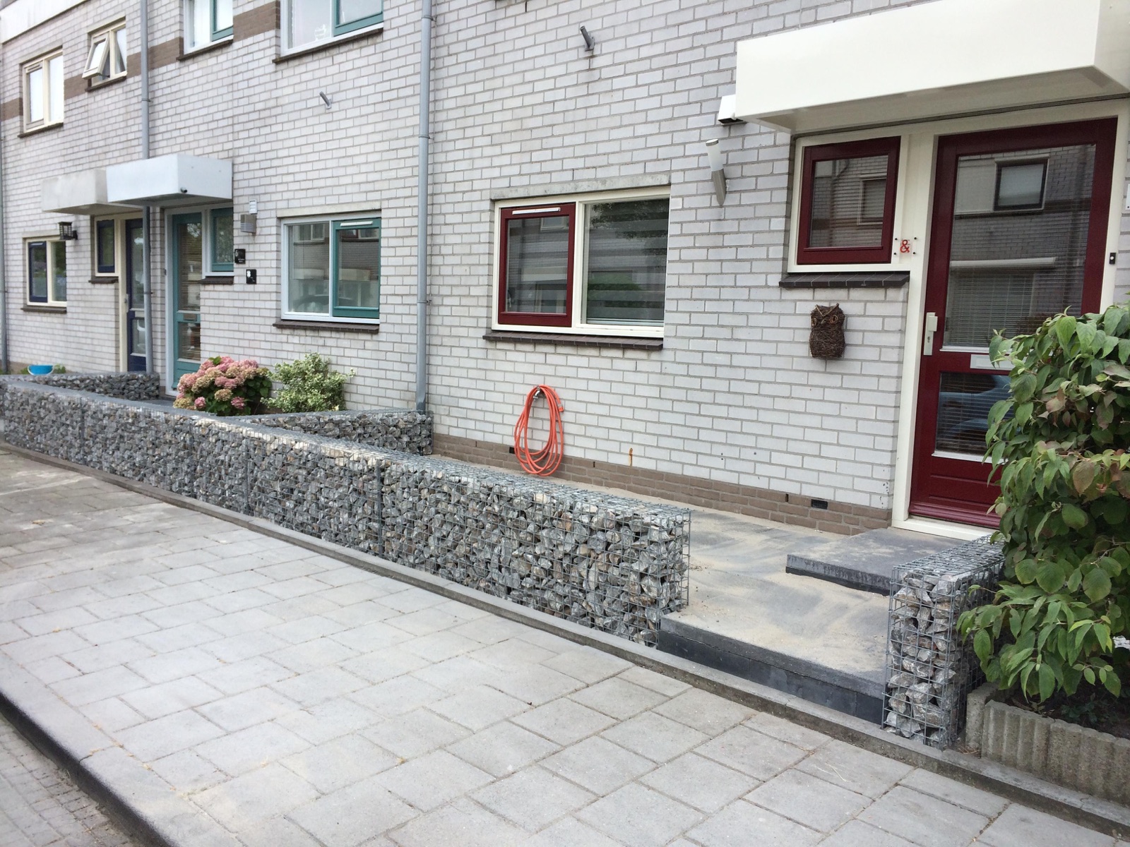 Begroeide schanskorfwand met plantenrand in de voortuin